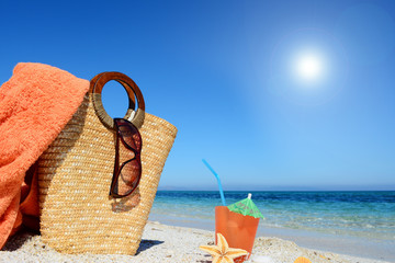 Cocktail and straw bag under a shining sun