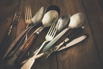 Cutlery, forks, spoons, and knives on a wooden background vertical