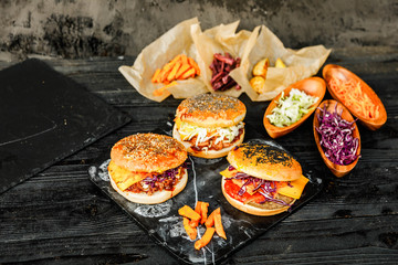 Homemade Pulled Pork, Beef and Vegan Burgers with Chia, Black, White sesam, flax seeds with coleslaw salad red, white cabbage, carrot, purple, orange sweet potatoes in paper, grey concrete background