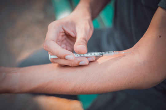 man drugs addicted with syringe injecting heroin in his arm. drugs and disease concept.