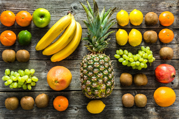 Table with fruit, tropical variety of mixed fruits on wooden background, healthy food and clean eating concept - obrazy, fototapety, plakaty
