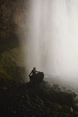 Woman wearing a black dress by a waterfall in Iceland - 204636377