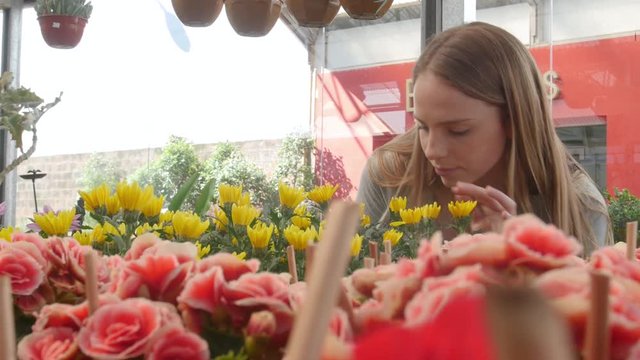 Young woman shopping for flowers at nursery close up