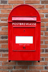Danish red mailbox on brown brick wall