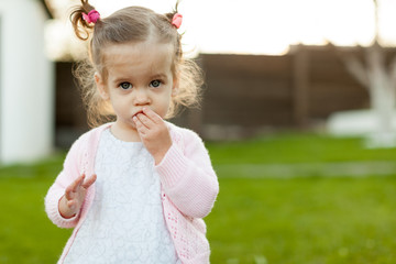 soft focus photo of little curly girl with two tails walking in the backyard on the green grass