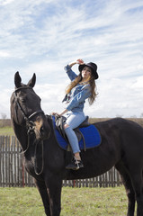 the girl is walking in nature on horseback on a black horse