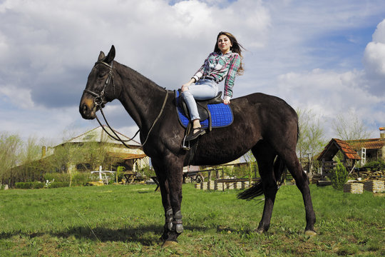 the girl is walking in nature on horseback on a black horse