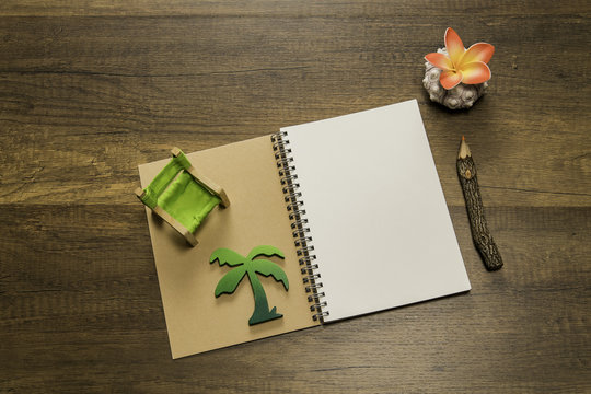 Opened notebook with green beach chair and palm tree with pencil and flower