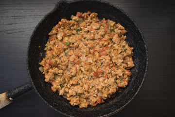 Appetizing fried minced meat with vegetables and greens in rustic old frying pan close-up