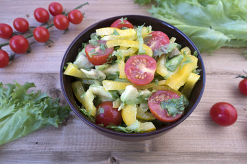 Appetizing vegetable salad consisting of tomatoes, avocado, yellow sweet pepper, lettuce leaves.