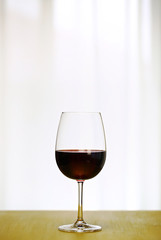 Single Red Wine in Bordeaux-shaped glass on the center of Copper Counter Top, with defocused Window and White Curtain, plain background, No decoration, Ambient Nature Day Lighting Studio image 1