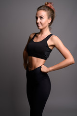 Fototapeta premium Young beautiful woman ready for gym against gray background