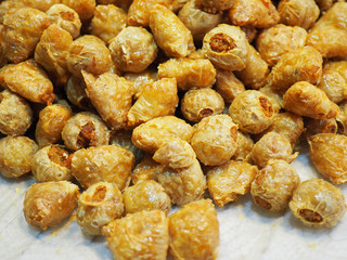 Pile of cut Chinese Thai local traditional style golden yellow brown deep fried chicken and crab meat roll filled in bean curd sheet (Hoi Jo) pieces on white paper table for absorbing exceeding oil