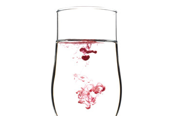A drop of red and black liquid was just poured into a clear wineglass
