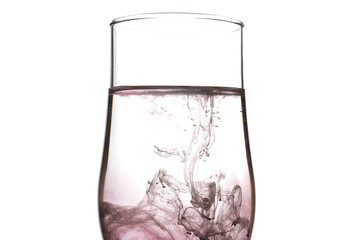 A drop of red and black liquid was just poured into a clear wineglass