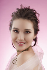 Closeup portrait of a beautiful smiling asian girl wearing pink veil on her shoulders and a choker on her neck