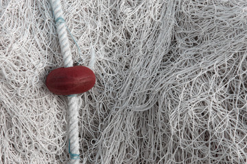 Gros plan de mailles de filet de pêche emmêlé sur un port avec un flotteur rouge et un espace...