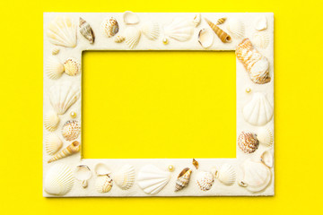 Photo frame with shells on  yellow color paper texture background. The concept of a summer vacation.  Summer Flatlay Image