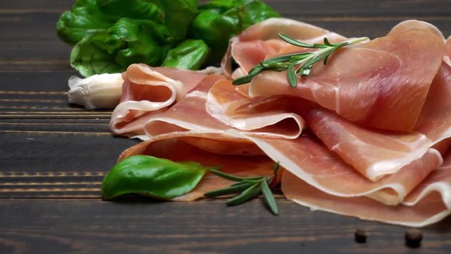 sliced prosciutto or jamon meat on wooden background