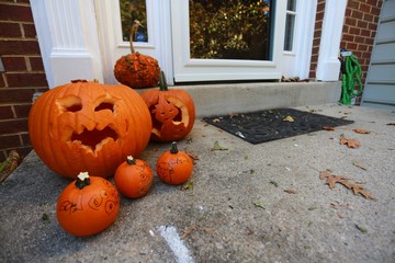 Obraz premium Large and Small Halloween Jack-o-Lantern Pumpkins on Doorstep of Town House in Burke, Virginia with Red Brick Walls