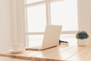 Computer and headphones on the table brown wood suitable for sitting or listening to music in a white room.