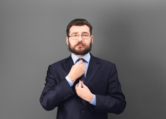 Portrait of confident mature man in elegant suit on color background