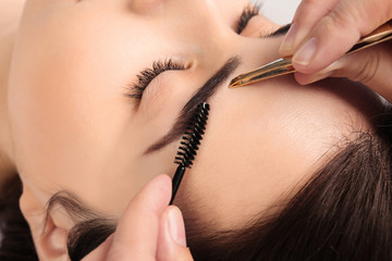 Young woman having professional eyebrow correction procedure, closeup