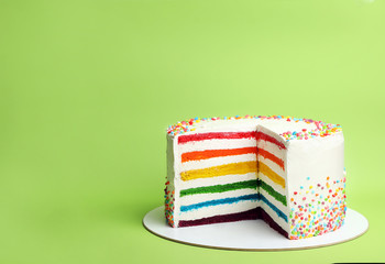 Delicious rainbow cake on color background