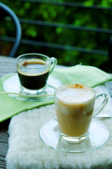 Hot Cappuccino Coffee and Hot Americano coffee on wooden table with cozy coffee shop.have some space for write wording