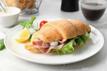 Tasty croissant sandwich with sausage  on table