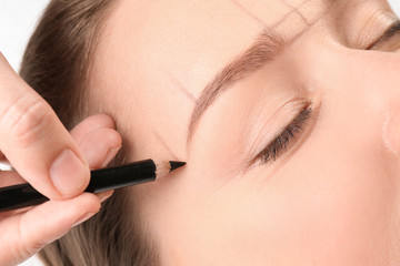 Young woman having eyebrow correction procedure in beauty salon, closeup