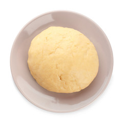 Plate with raw dough on white background, top view