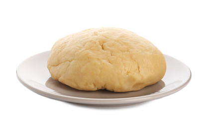 Plate with raw dough on white background
