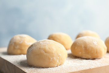 Fresh raw dough with flour on wooden board