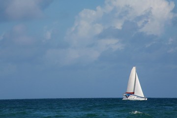 Fototapeta premium Sailboat on the Atlantic Ocean in Florida Frame Right in the Afternoon with Mostly Blue Sky and Some Clouds Overhead