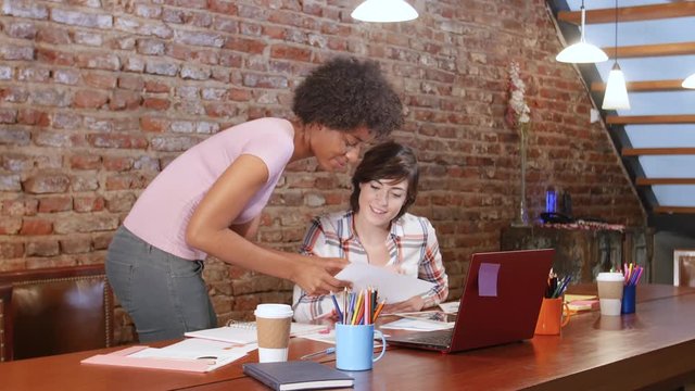 Two female professionals working on start up company at coworking location