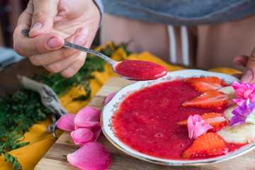 Woman hands taking (eating) raw vegan strawberry yogurt with bananas. Sweet healthy dessert on breakfast morning. Vegetarian food