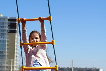 child clings to the rope ladder on the Playground