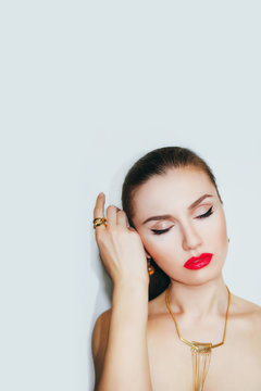 The beautiful woman with red lips and beautiful makeup in a gold necklace and a ring on her finger.