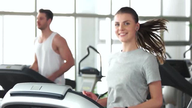 Young happy woman working out at gym. Slow motion young woman training at fitness club and looking at camera. Weight loss concept.