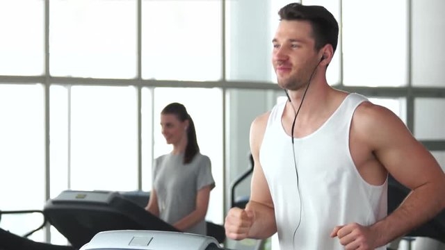 Young athletic man running on treadmill. Handsome muscular guy working out at gym. Always be in fit.