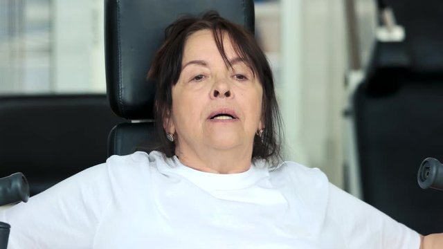 Senior woman doing chest exercise at gym. Close up elderly caucasian woman exercising at fitness gym to stay healthy. Exercises and longevity.