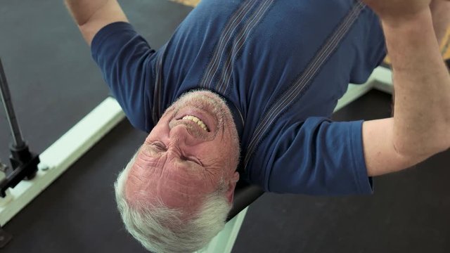 Senior man doing bench press exercise. Male pensioner lifting weight at gym close up. Reasons to strat lifting weights.
