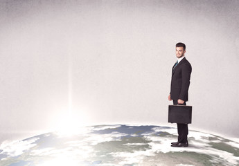 A young elegant office worker standing on top of a drawn world globe while celebrating his successful career concept.