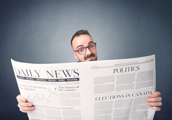 Young smart businessman reading daily newspaper