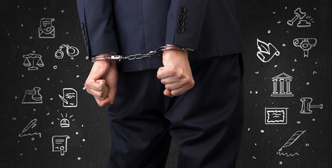 Chalk drawn courthouse symbols and close handcuffed hands in suit
