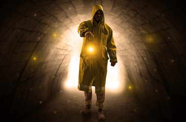 Ugly man in raincoat walking with glowing lantern in a dark tunnel