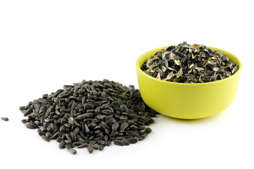 organic sunflower seeds pile isolated on white background. and husk, sunflower seed shell in a yellow bowl against white background