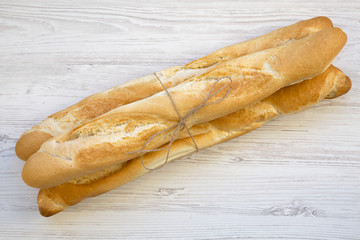 Fresh Baguettes on white wooden background, top view.
