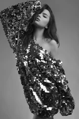 Sinnliche, schöne, brünette Frau in einem glänzenden Modekleid aus Pailletten © micro